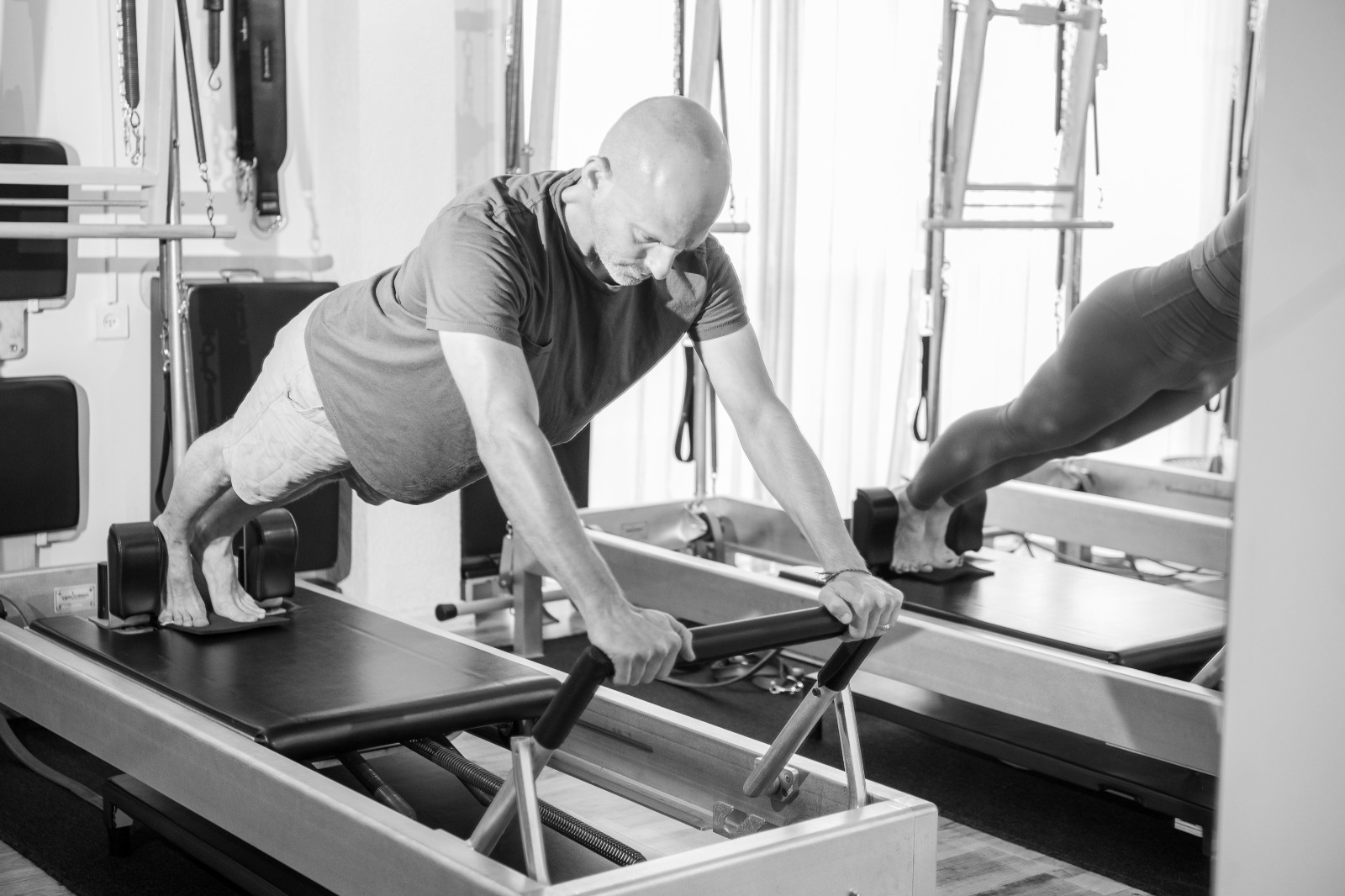 Lior in a long plank position on a Pilates reformer